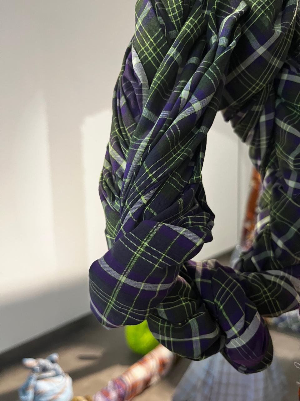 Detail of green and purple plaid sarong fabric wrapped and knotted around a frame